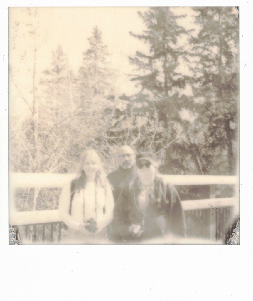 A Polaroid of three photographers standing on a bridge.
