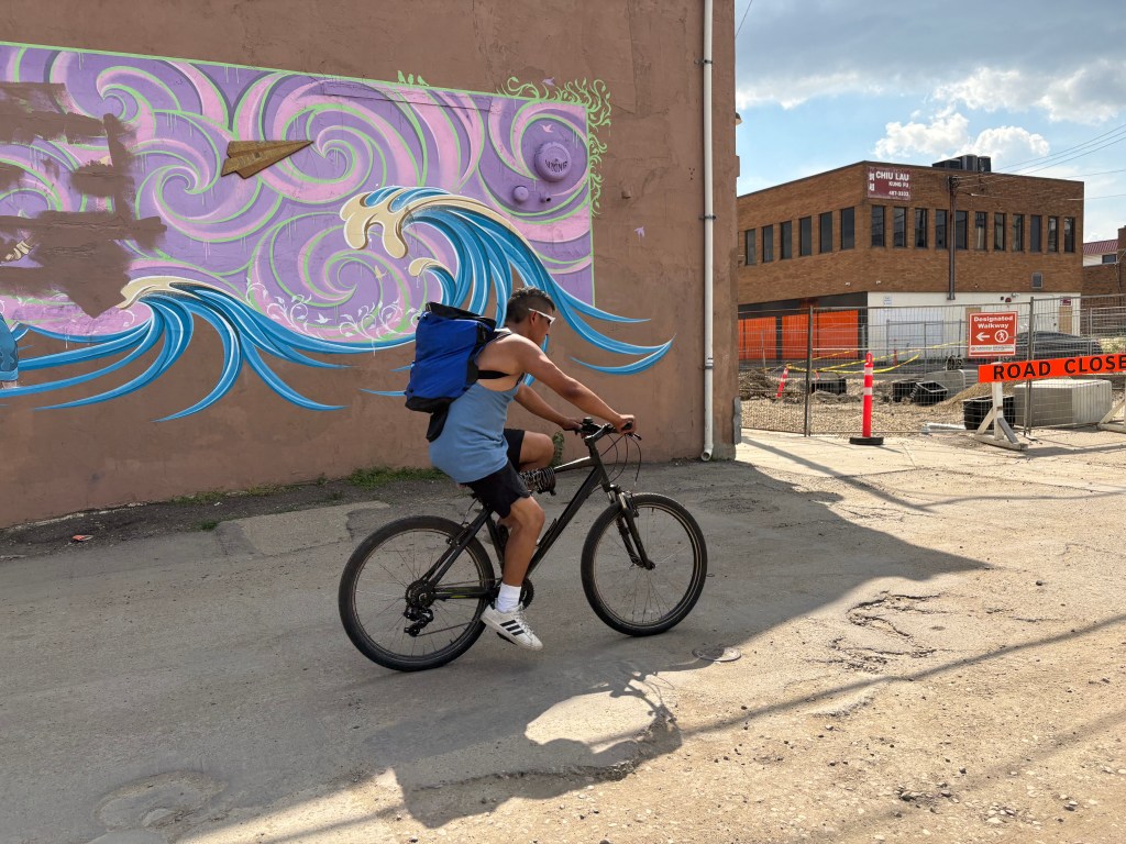 A cyclist passing a mural.
