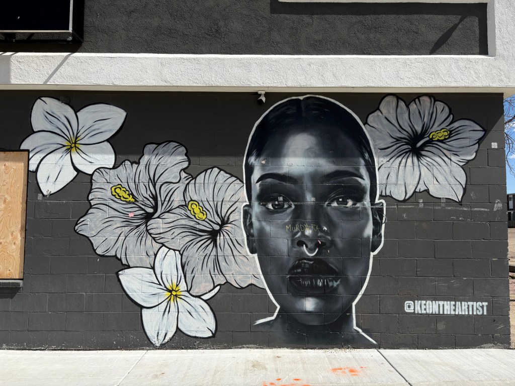 Mural featuring the face of a Black woman surrounded by flowers.