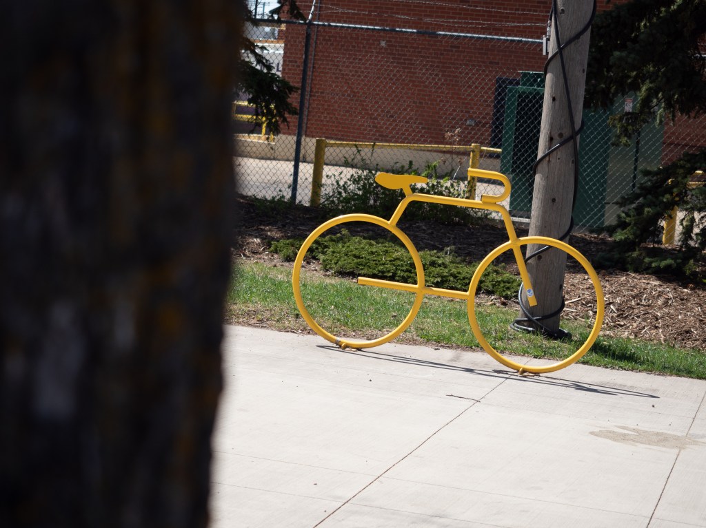 A yellow bicycle that is a piece of street art.